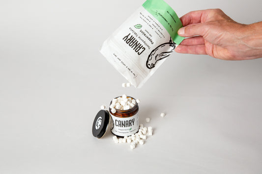 Canary toothpaste tablet glass jar getting refilled by our compostable refill pouch