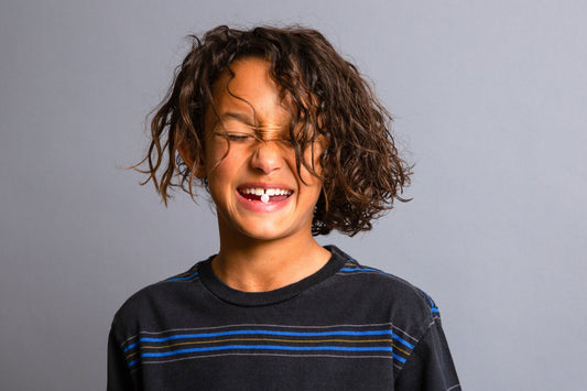 Kid smiling with toothpaste tablet between teeth.