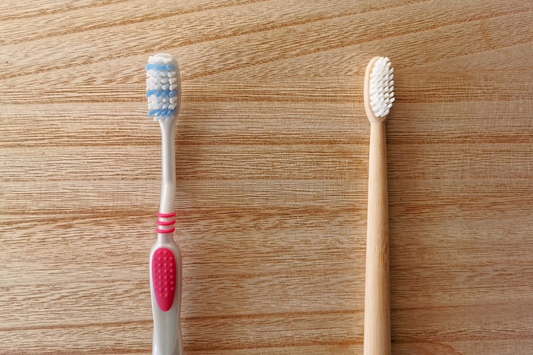 Plastic toothbrush next to a bamboo toothbrush