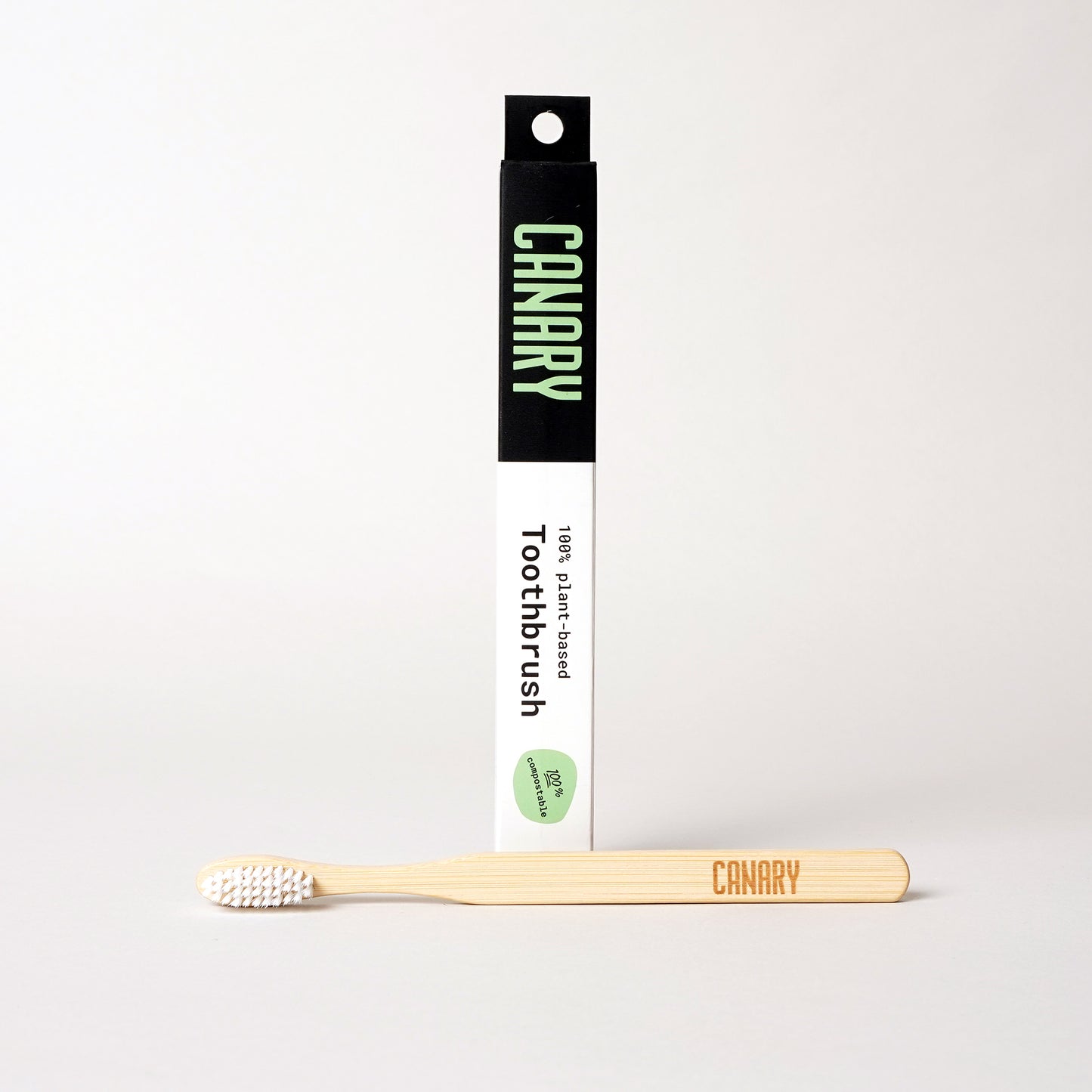 Canary plant-based and fully compostable bamboo toothbrush sitting next to the box. Single unit.