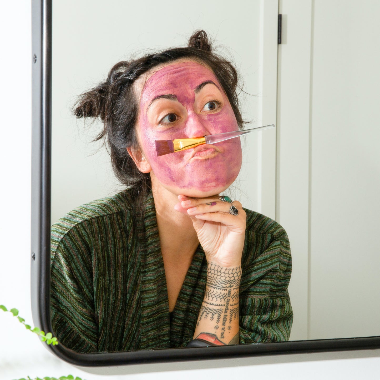 Woman making silly face using Canary Face mask in bathroom.