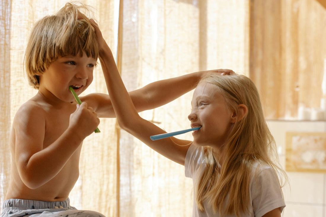 Two kids brushing their teeth and smiling at each other