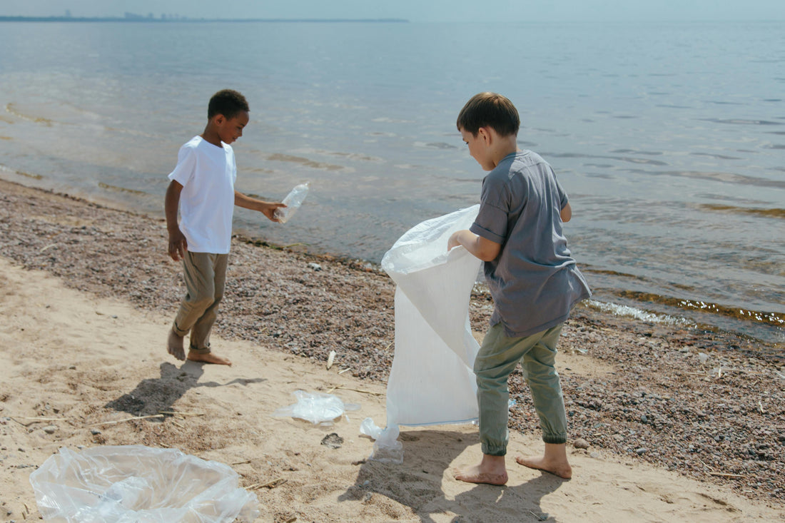 Two kids picking up trash on beach