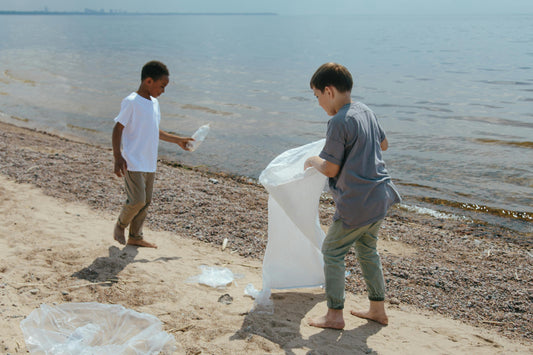 Two kids picking up trash on beach