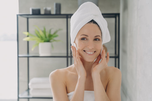 Women smiling in mirror doing self-care routine by using plastic-free products with quality ingredients.