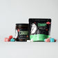 Front Image of Bubble Gum Flavored Toothpaste Tablets. Reusable glass jar of 126 tablets. And 63-count Plastic-Free and Compostable Pouch. Surrounded by bubble gum and toothpaste tablets. 