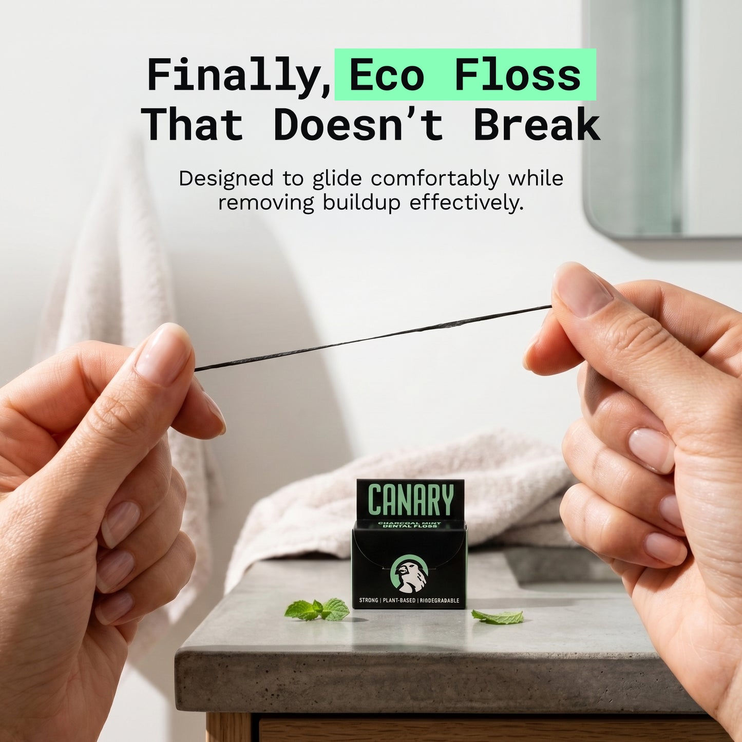 Image of hands pulling on canary dental floss showcasing the durability. With packaging on bathroom sink.