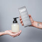 Image of Hand holding Fire Needle and Sage scent Foaming Hand Soap Starter Kit. And other hand holding eco-friendly refillable glass bottle. 