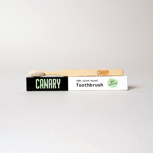 Canary plant-based and fully compostable bamboo toothbrush sitting on the box. Single unit. 
