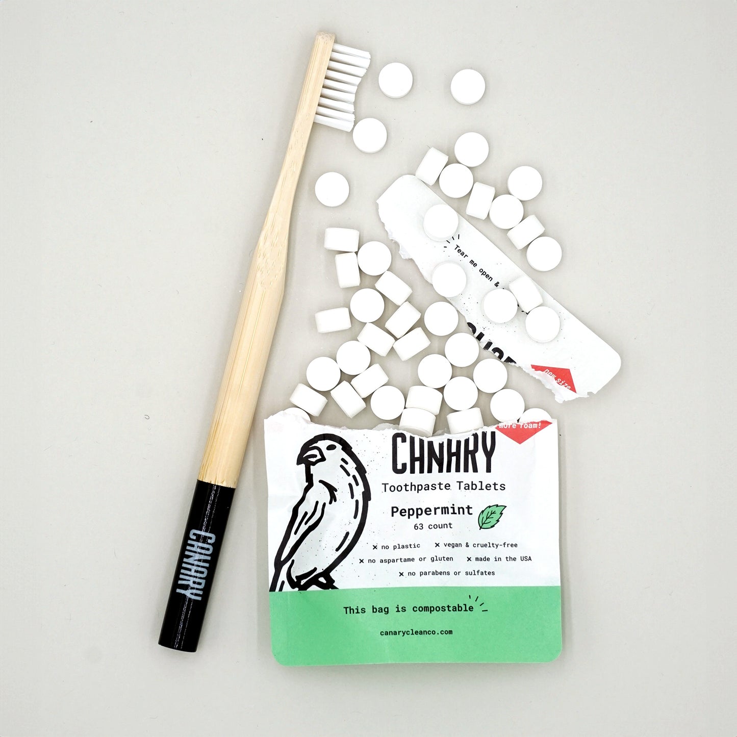 New and improved Canary Peppermint Toothpaste Tablets, 63ct compostable pouch, front view with black-tipped Canary toothbrush