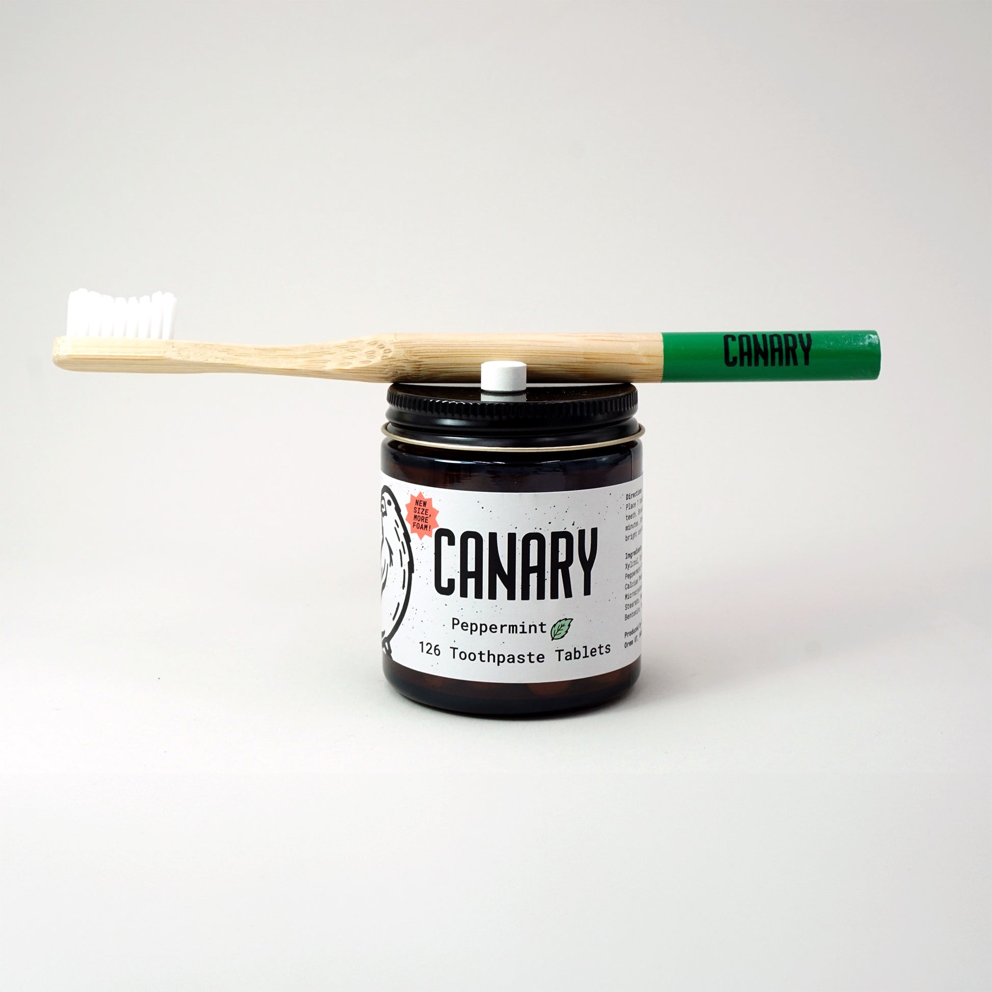 New and improved Canary Peppermint Toothpaste Tablets, 126 count jar, front view with green-tipped Canary toothbrush