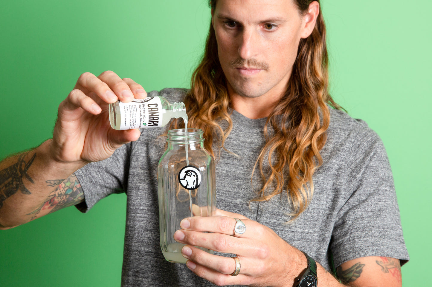 Kevin pouring Canary Peppermint Mouthwash Concentrate into a reusable glass mixing bottle